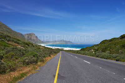 Buy stock photo Mountain, road trip and ocean highway with travel, holiday and countryside scenery in Cape Town. Nature, blue sky and asphalt on journey, vacation and outdoor adventure with beach, horizon and bush