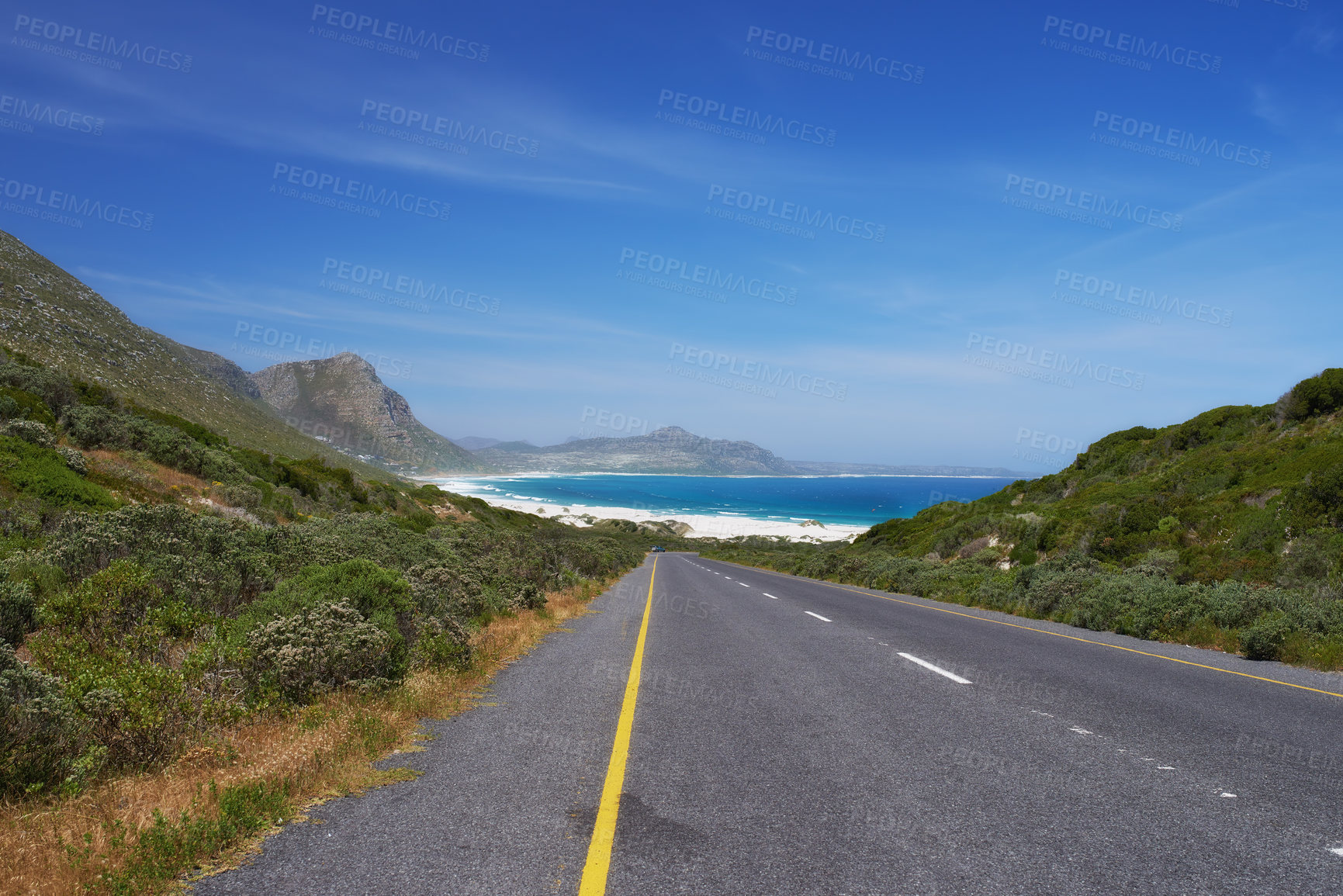 Buy stock photo Mountain, road trip and ocean highway with travel, holiday and countryside scenery in Cape Town. Nature, blue sky and asphalt on journey, vacation and outdoor adventure with beach, horizon and bush