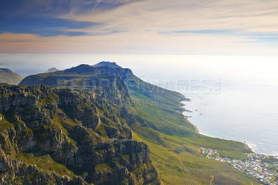 Buy stock photo Mountain, island and cloudy sky at ocean cliff with natural landscape, hill and beach at travel location. Nature, city and sustainable environment with earth, sea and sunset at holiday destination