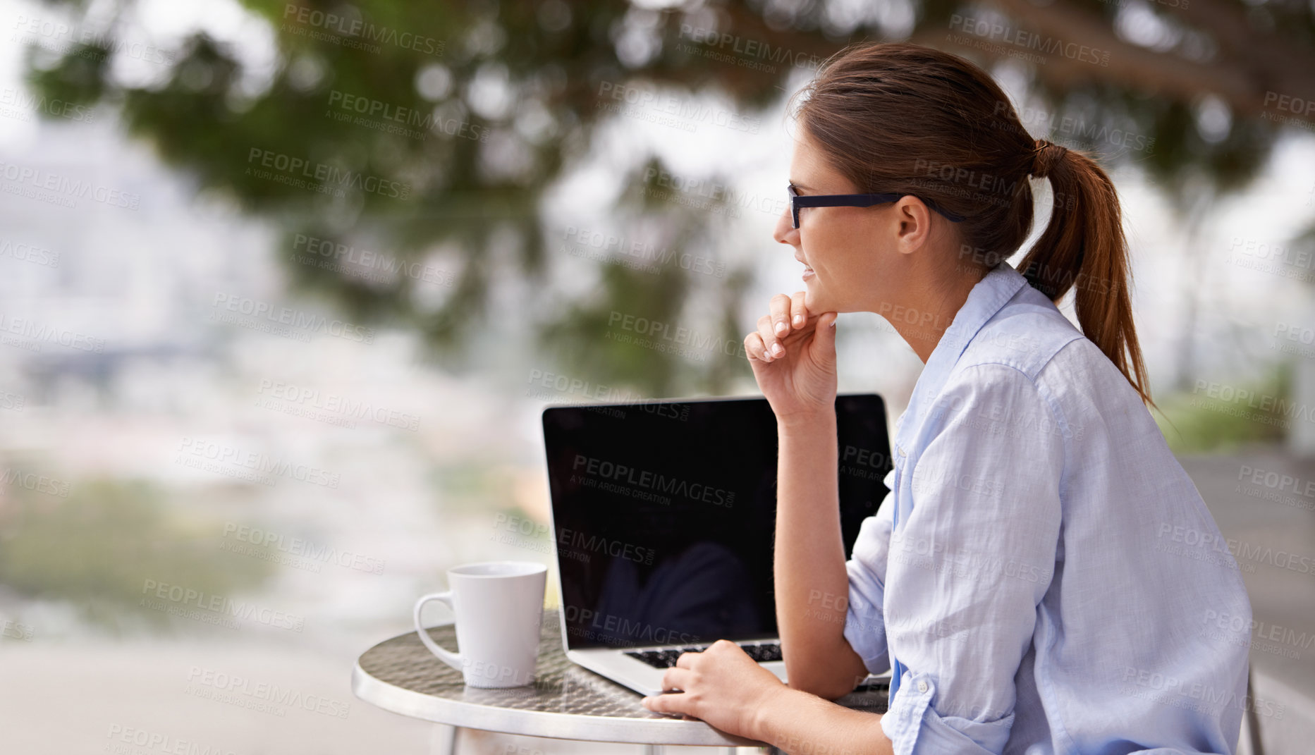 Buy stock photo Shot of an attractive young woman using her laptop outdoors