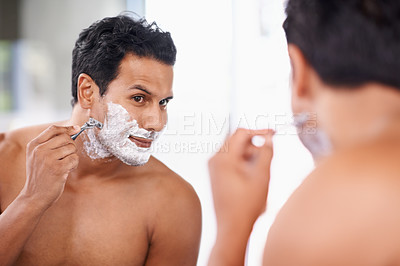 Buy stock photo A handsome young man shaving in the bathroom