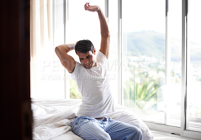 Buy stock photo Cropped shot of a young man stretching in bed while waking up