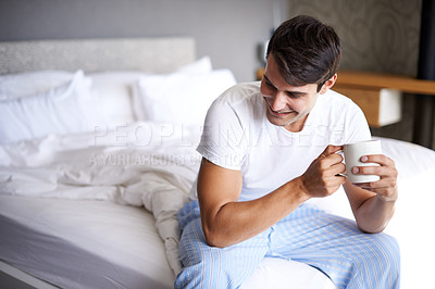 Buy stock photo Cropped shot of a handsome young man drinking coffee on the edge of his bed