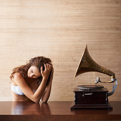 Buy stock photo An attractive young woman in lacy lingerie sitting beside a gramophone