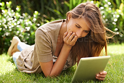 Buy stock photo Shot of a woman enjoying using her digital tablet in the outdoors