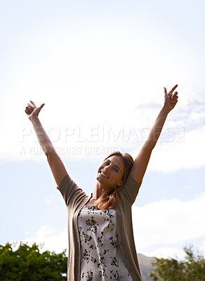 Buy stock photo Shot of a beautiful young woman with her arms raised outdoors