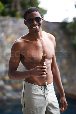 Buy stock photo A young man smiling at the camera while holding a beer