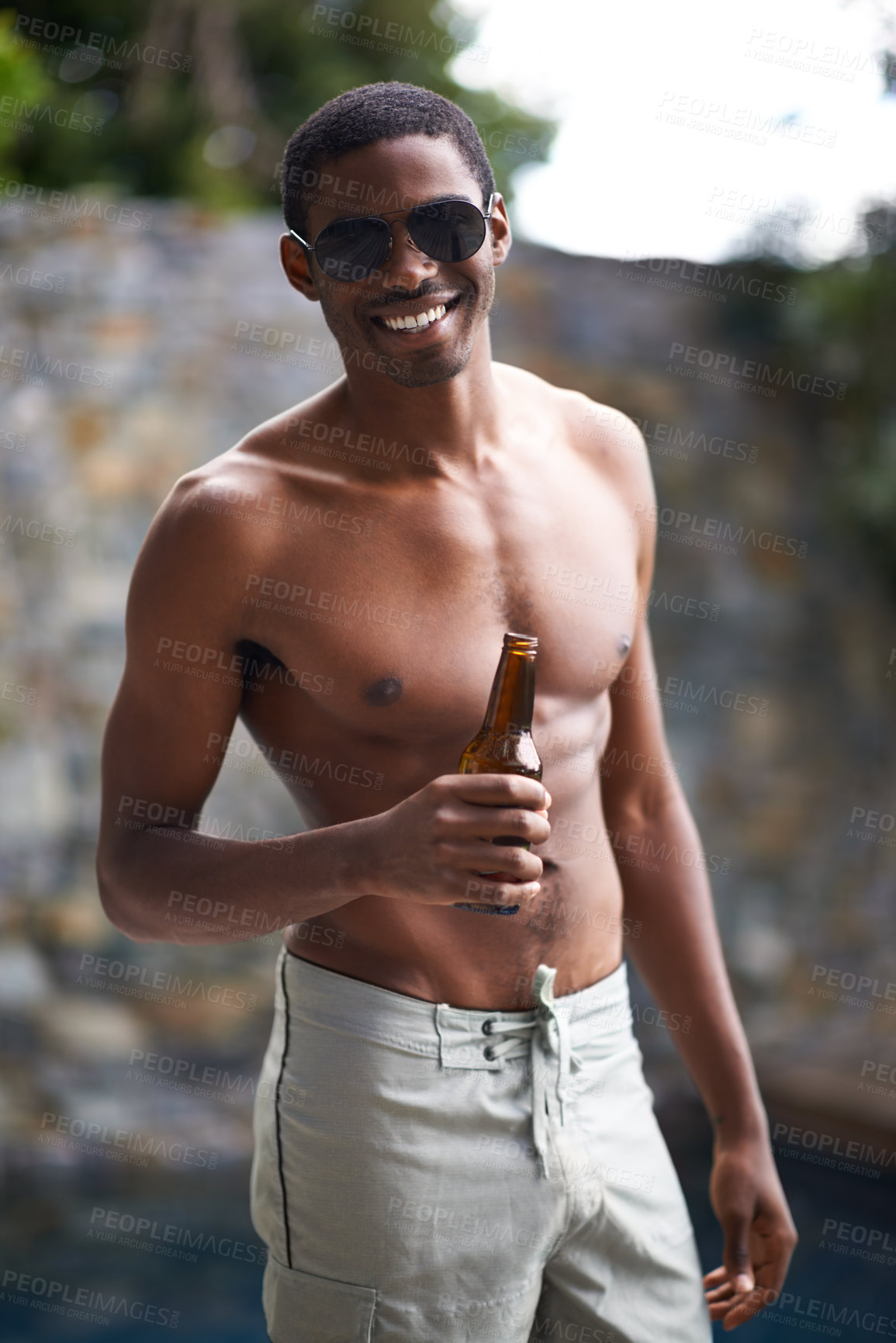 Buy stock photo A young man smiling at the camera while holding a beer