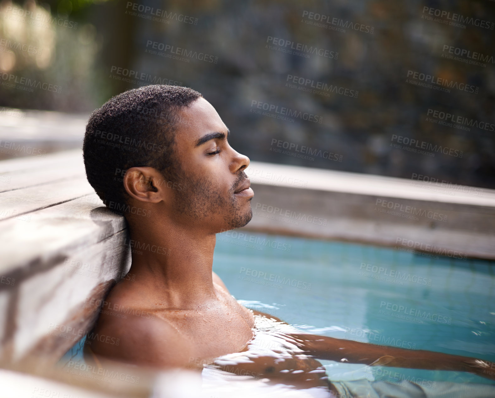 Buy stock photo Shot of a handsome young man relaxing in a pool