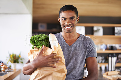 Buy stock photo African man, paper bag and groceries in home kitchen with smile for discount, deal and nutrition choice. Person, shopping and happy in apartment for product, sale and ready with portrait for cooking