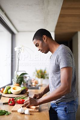 Buy stock photo Shot of a handsome ethnic man preparing vegetables indoors