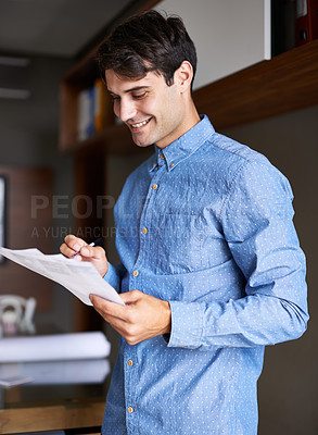 Buy stock photo Shot of a handsome young businessmen holding some paperwork in his hands