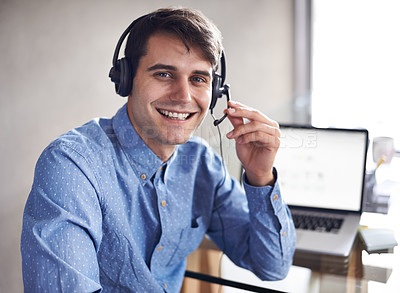 Buy stock photo Portrait of a young businessman wearing a headset while sitting at his desk