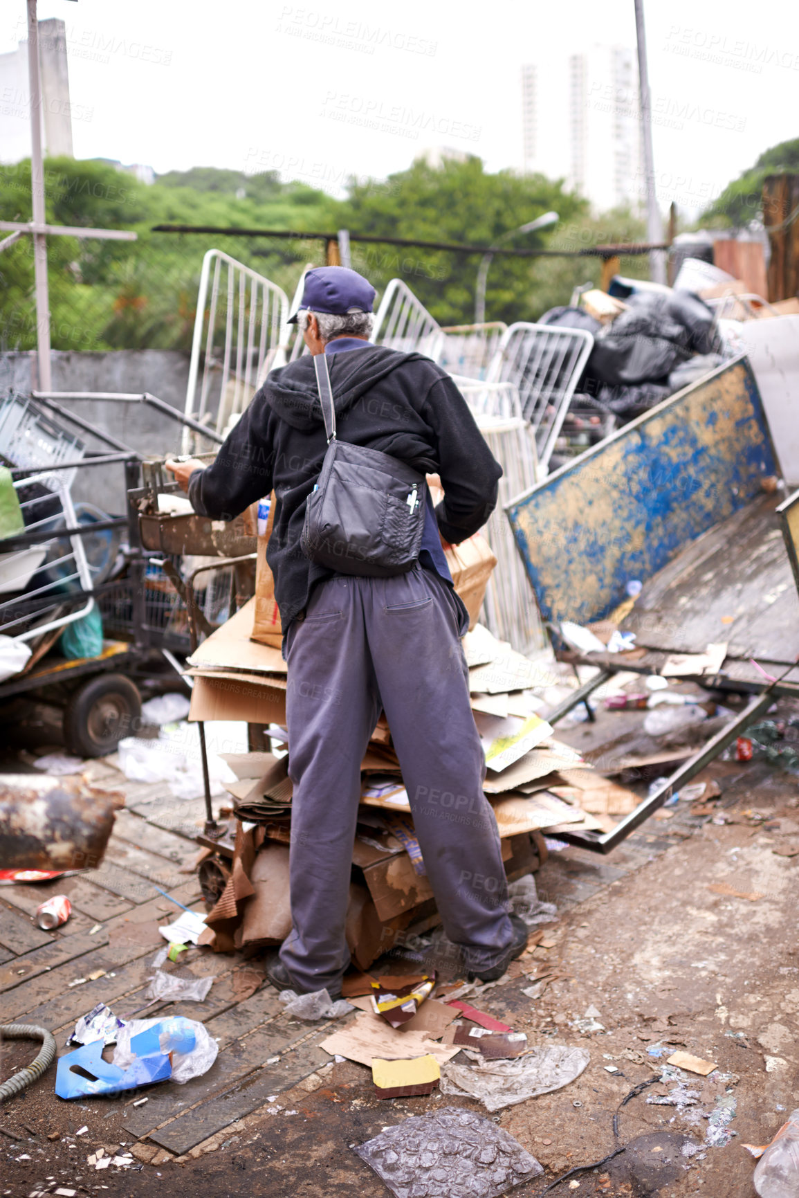 Buy stock photo Man, worker and recycling of garbage for waste management in city with rear view, bag and scrapyard. Person, back and search by dumpster site for scrap, rubbish and trash in neighborhood for litter