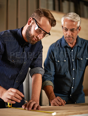 Buy stock photo Wood, learning and carpentry apprentice with mentor in designer furniture manufacturing workshop. Mentorship, senior carpenter and young man, measuring tape and focus on teaching sustainable business