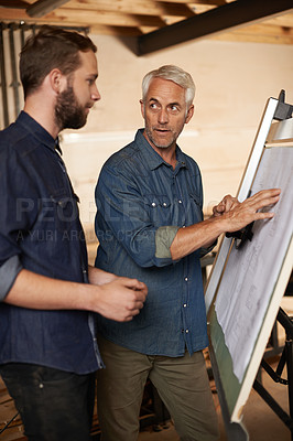 Buy stock photo Carpenter, team and men with blueprint for planning, construction or building. Engineer, apprentice and mentor with design, drawing and senior father teaching serious son in discussion at workshop