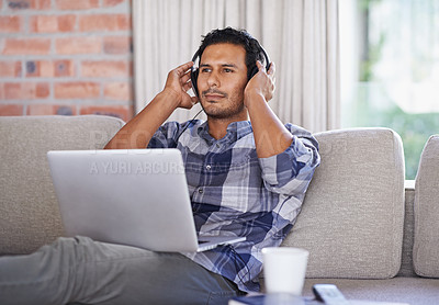Buy stock photo Man, laptop and living room with home, headset and internet for relax and streaming. Indian person, web and tech with house, lounge or apartment for listen to music and connectivity with subscription