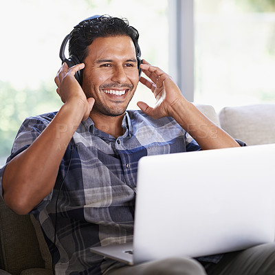 Buy stock photo Man, laptop and living room with headphones, smile and internet for relax and streaming. Indian person, web and tech with house, lounge or apartment for listen to music or podcast with subscription