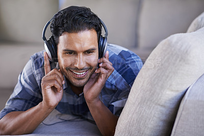 Buy stock photo Man, headphones and listening to song on couch, relax and streaming radio for music or sound. Happy male person, home and lying on sofa for peace, comfortable and hearing jazz playlist on weekend