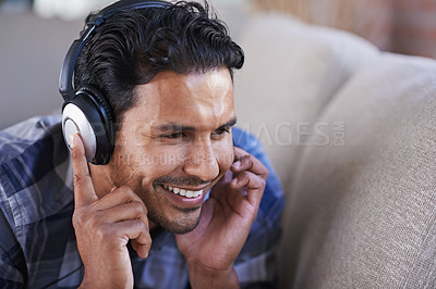 Buy stock photo Man, headphones and listening to music on sofa, relax and streaming radio for audio or sound. Happy male person, home and lying on couch for peace, comfortable and hearing rock playlist on weekend