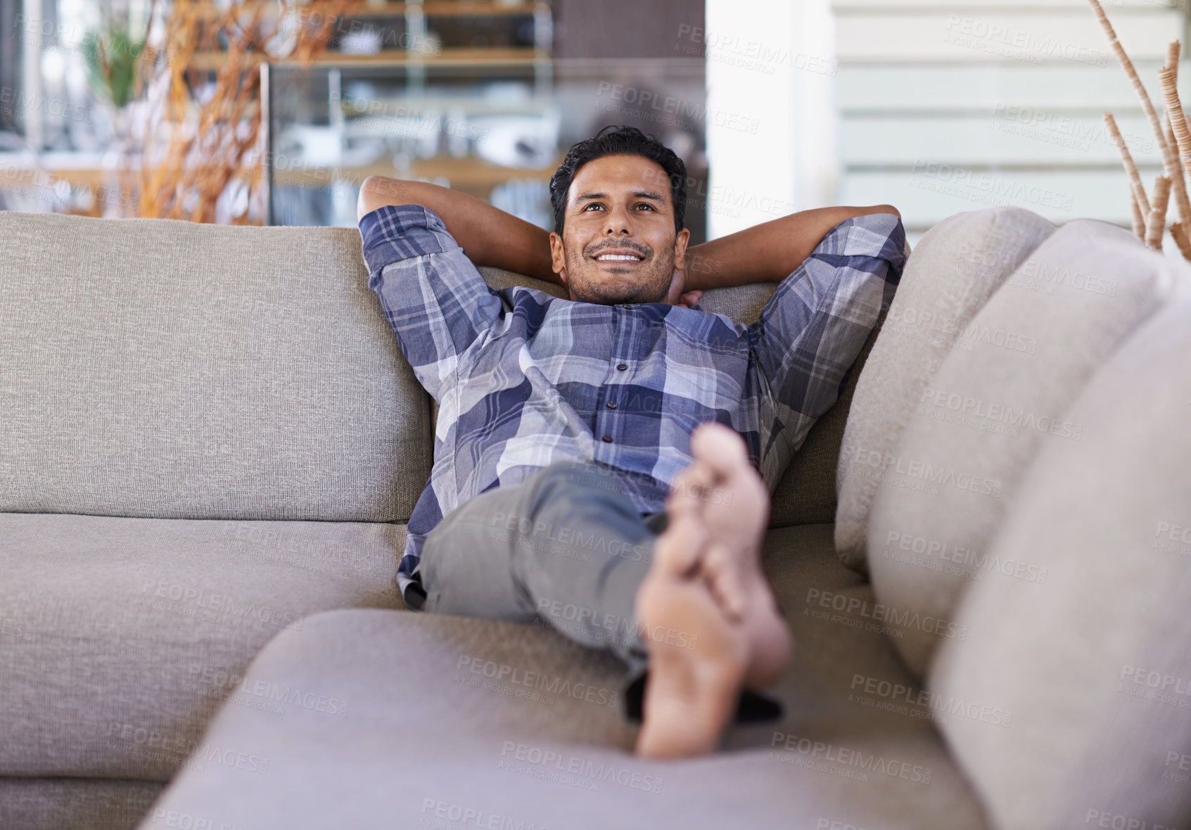 Buy stock photo Shot of a young ethnic man relaxing indoors on his couch