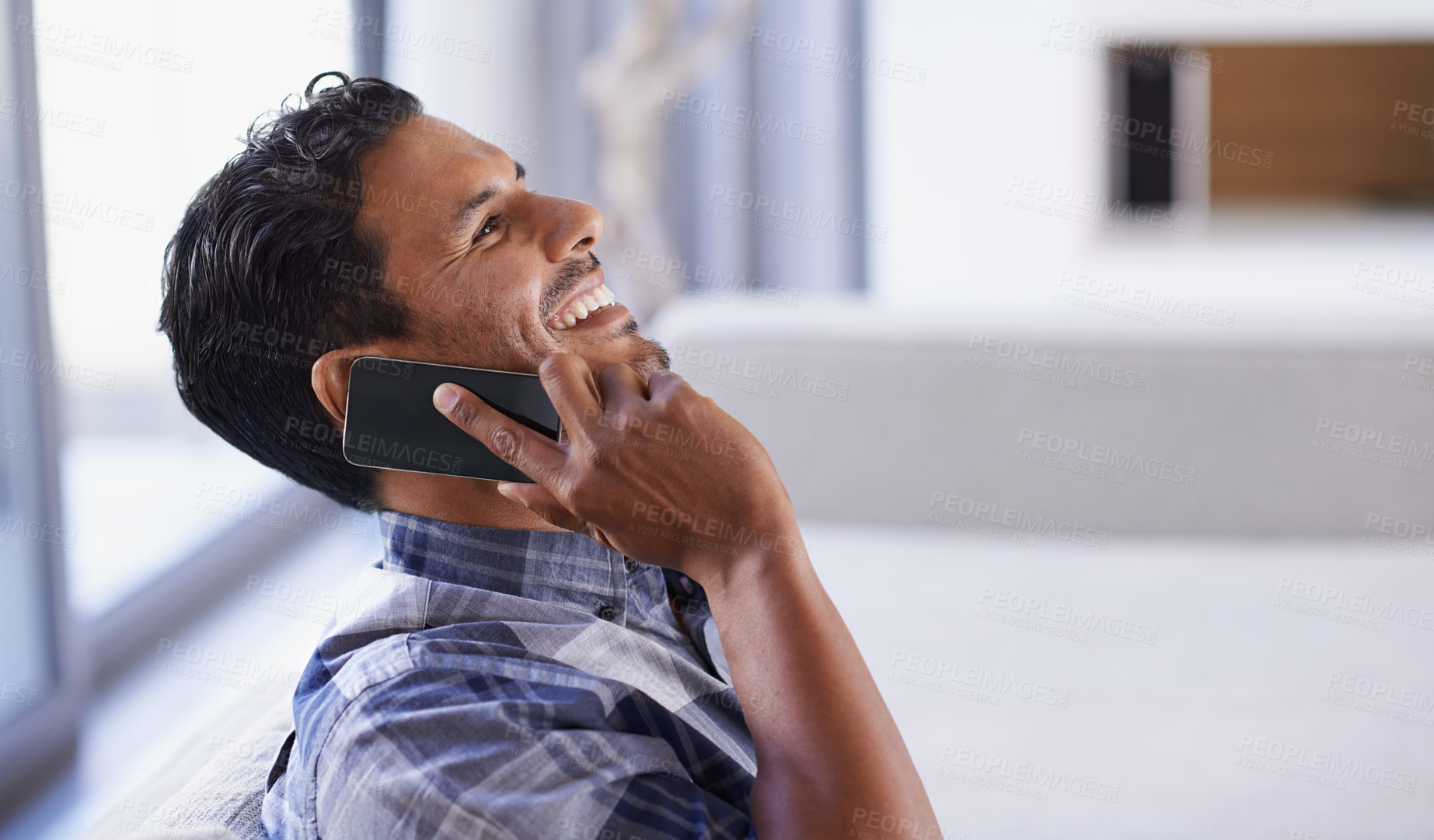 Buy stock photo Man, smartphone and laugh on sofa for phone call, funny conversation and communication in living room. Indian person, relax and technology in apartment for discussion, joke and mobile contact