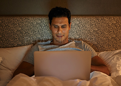Buy stock photo A young man working on his laptop in bed