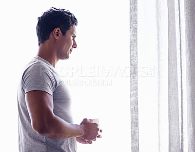 Buy stock photo Shot of a handsome man looking pensively out the window while drinking coffee