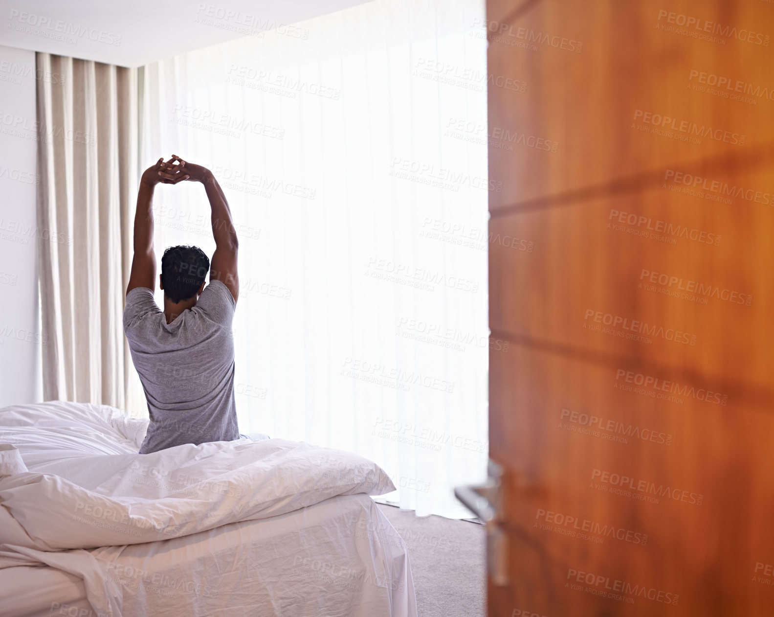 Buy stock photo A young man stretching out after waking