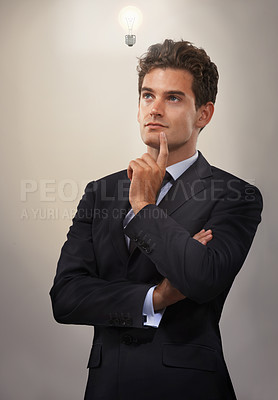 Buy stock photo Businessman, suit and thinking in studio with lightbulb for inspiration, ideas and creativity in career or job. Young man, attorney or executive with finger on chin for solution, plan and answer  