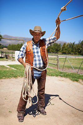 Buy stock photo Cowboy, ranch and farmer in outdoor, sun and straps for wrangler and Texas lasso at stable. Mature man, wild west and summer in agriculture, hat and male person with rope in farm job and environment