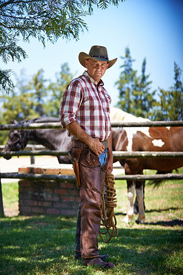 Buy stock photo Portrait, cowboy and man at farm with rope in the rural countryside with horses in Texas. Ranch, confidence or serious person in western hat outdoor in casual clothes in nature at stable with animals