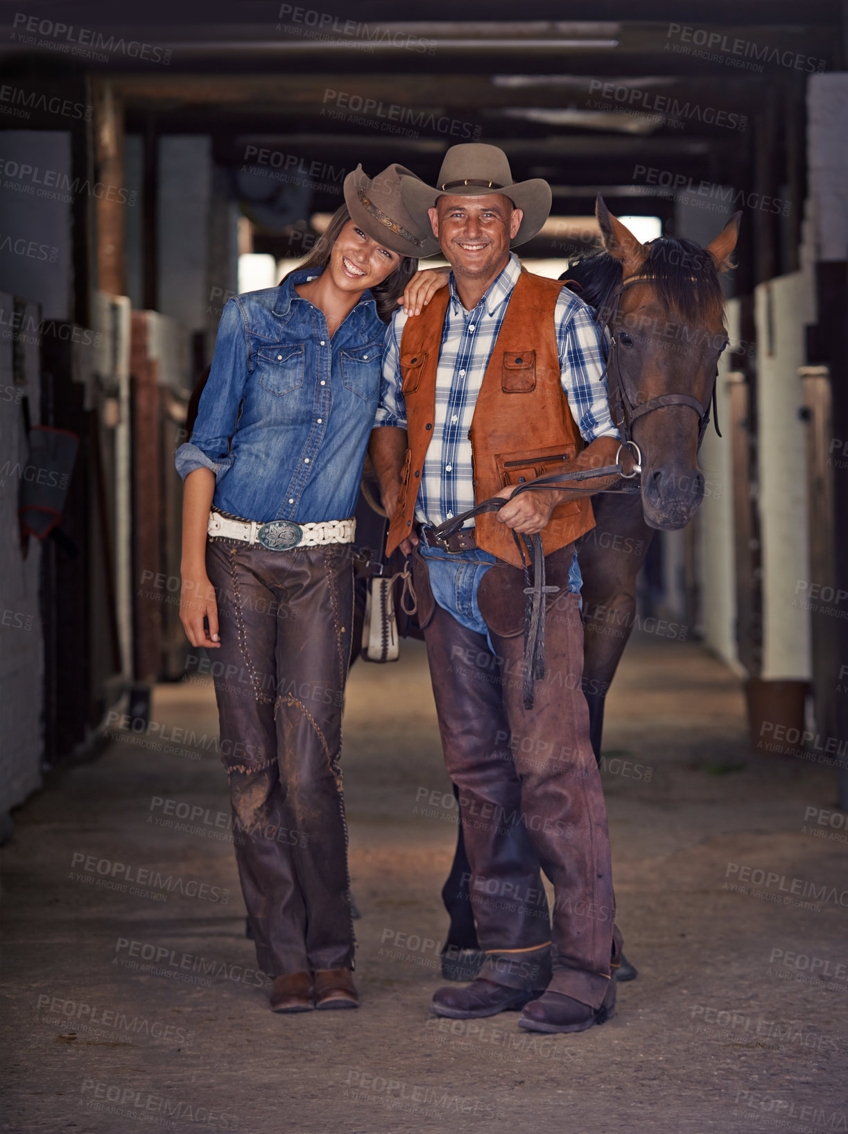 Buy stock photo Shot of a cowboy and cowgirl leading a horse out of a stable