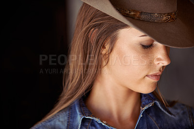 Buy stock photo An attractive young cowgirl standing in the stables 