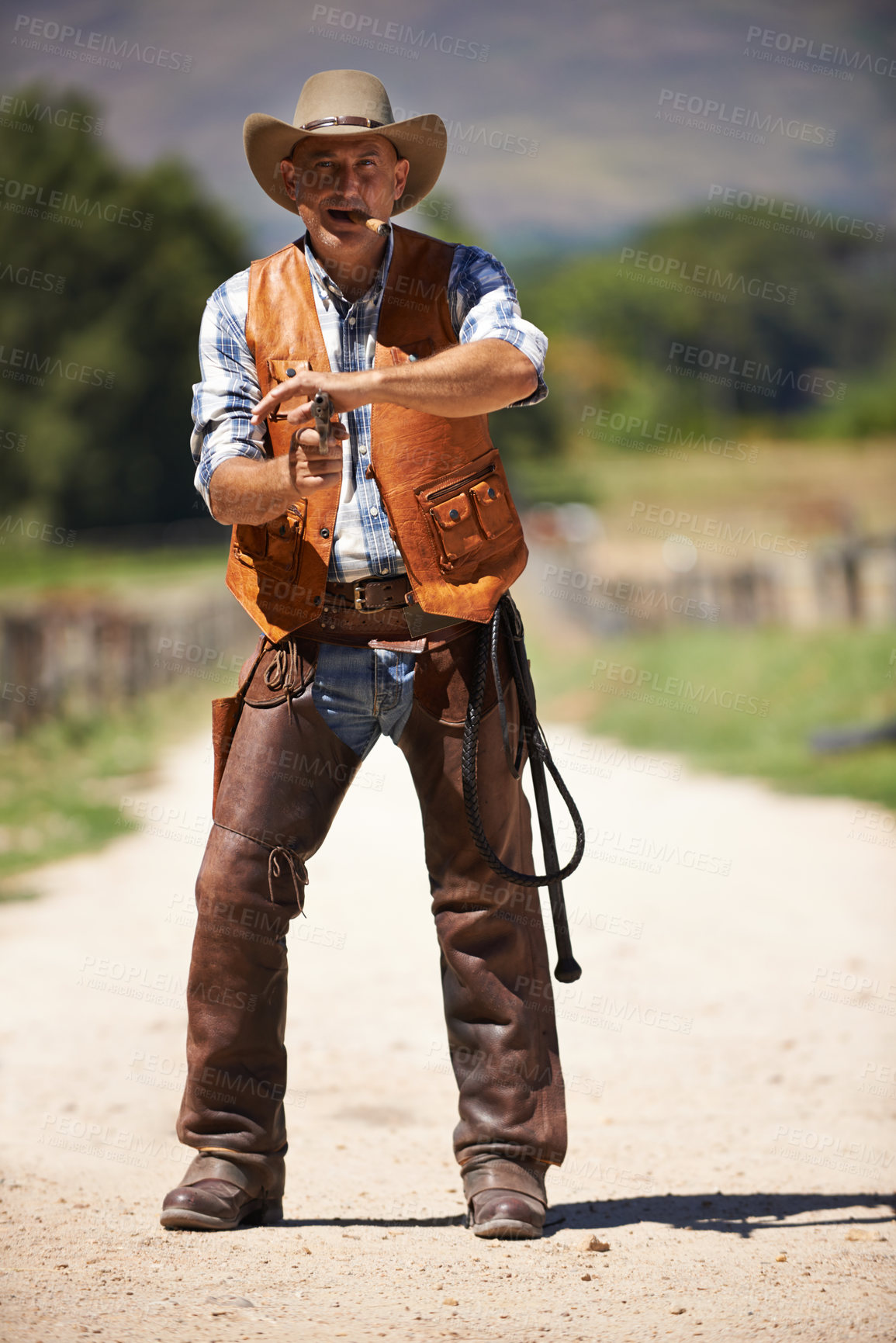 Buy stock photo A mature cowboy outdoors with his gun drawn