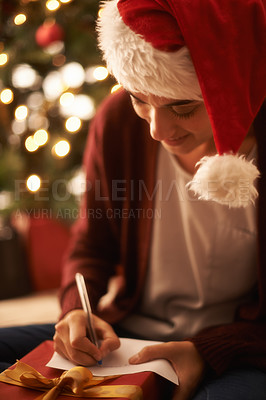 Buy stock photo Woman, writing letter and Christmas with smile by tree, present or santa hat with message for festive wish. Girl, person and paper with notes, gift or package with kindness, celebration and xmas card