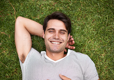 Buy stock photo Portrait, man and lying on grass to relax, wellbeing and happiness in peaceful garden retreat. Confident, male person and smile on ground, carefree and positive to rest, leisure and recreation