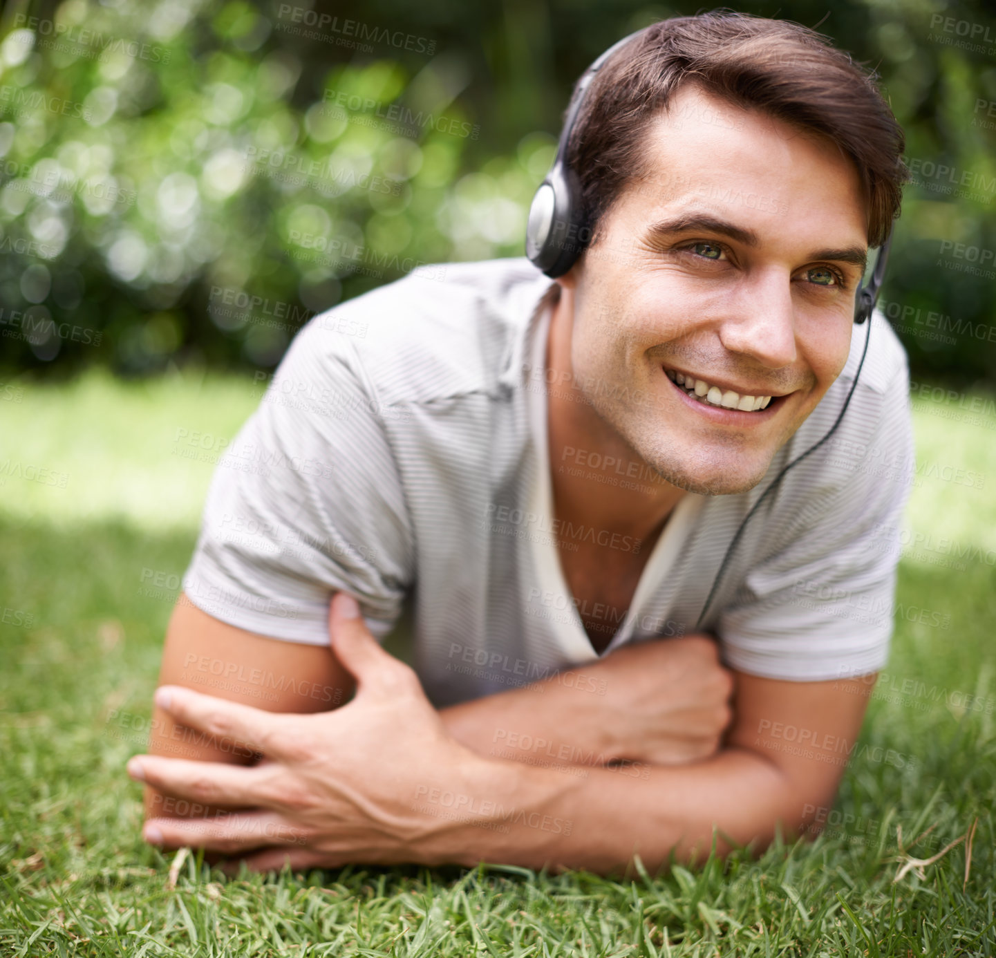 Buy stock photo Man, headphones and grass with smile, relax and music in park or garden. Student, rest and audio for podcast, wellness and summer with happiness and thinking or planning on break outside on lawn