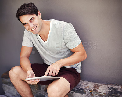 Buy stock photo Portrait of a handsome young man using a digital tablet in the studio