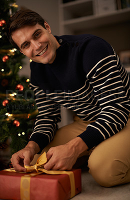 Buy stock photo Portrait, Christmas tree and man wrapping gift in home for preparation of holiday event of tradition. Gift, present and smile with happy young person in apartment for December celebration or vacation