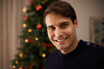Buy stock photo Portrait, home and man with smile for Christmas in living room with decorations on tree for celebration. Apartment, happiness and male person with joy for tradition in house, holiday and bokeh