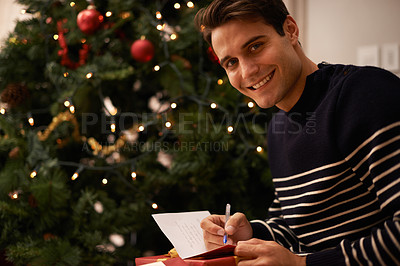 Buy stock photo Portrait, Christmas tree and man writing on present in home for preparation of holiday event of tradition. Box, gift card and smile with young person in apartment for December celebration or vacation
