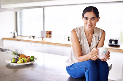 Buy stock photo Shot of an attractive young woman sitting on her kitchen counter and drinking coffee