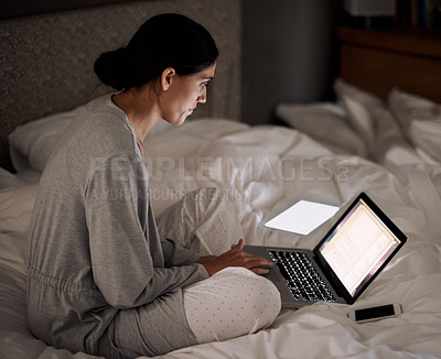 Buy stock photo A young woman working on her laptop in bed