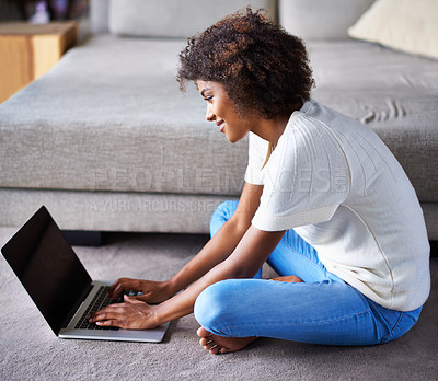 Buy stock photo Smile, laptop and black woman on floor working on freelance creative project in living room. Happy, technology and young African female designer typing on computer for research on rug in apartment.