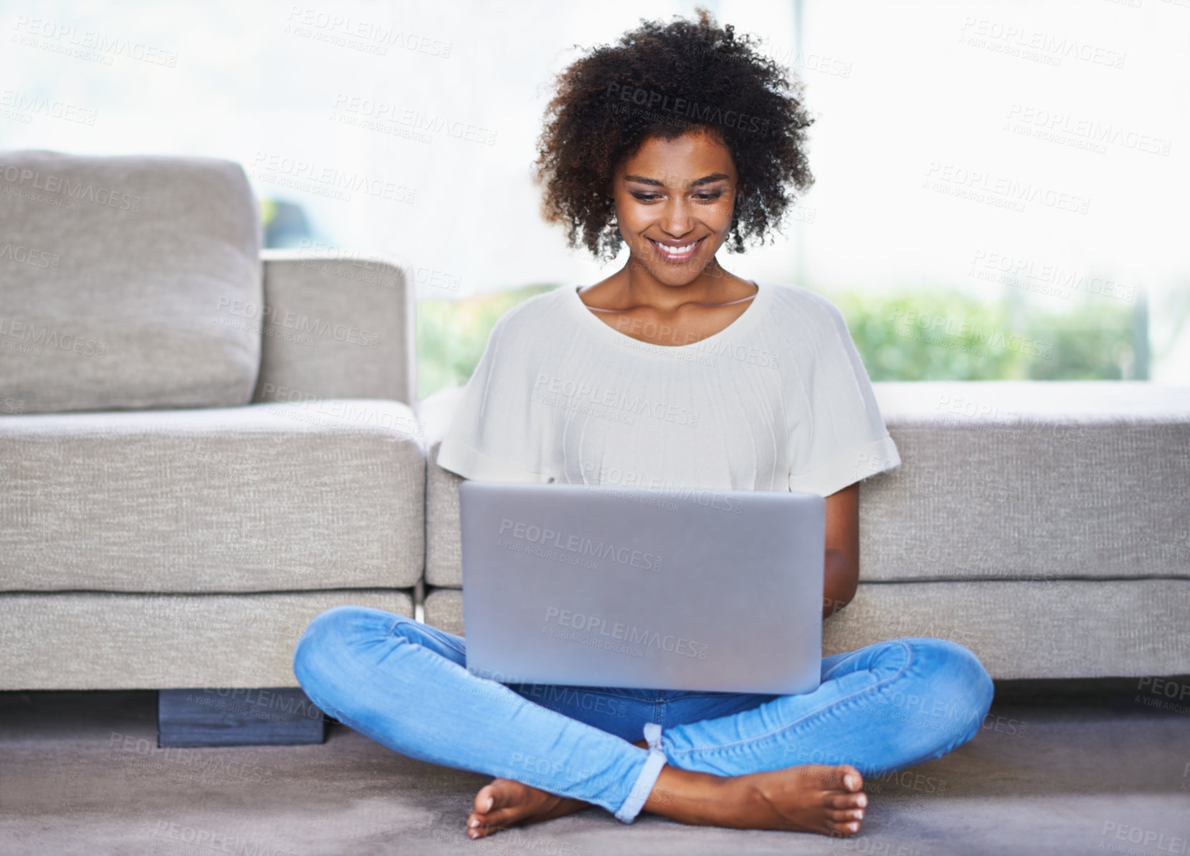 Buy stock photo Shot of a young woman using a laptop while relaxing at home