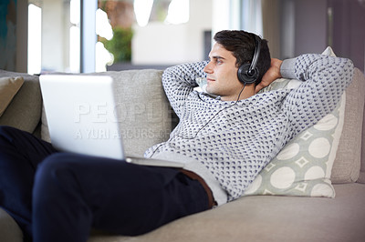 Buy stock photo Shot of a young man listening to music through his laptop