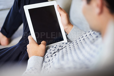 Buy stock photo Rearview shot of a young man using his digital tablet