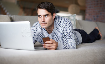 Buy stock photo Man, laptop and smartphone at home on sofa for remote work as freelance, journalist and online research for newspaper. Male person, living room and focus on internet with information for article.