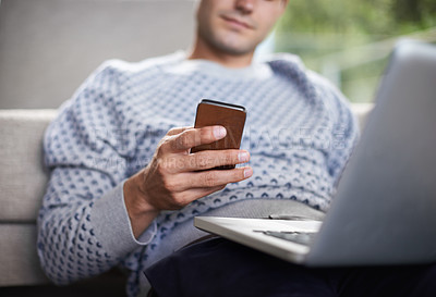 Buy stock photo Cropped shot of a man sitting on his living room floor with his laptop and mobile phone